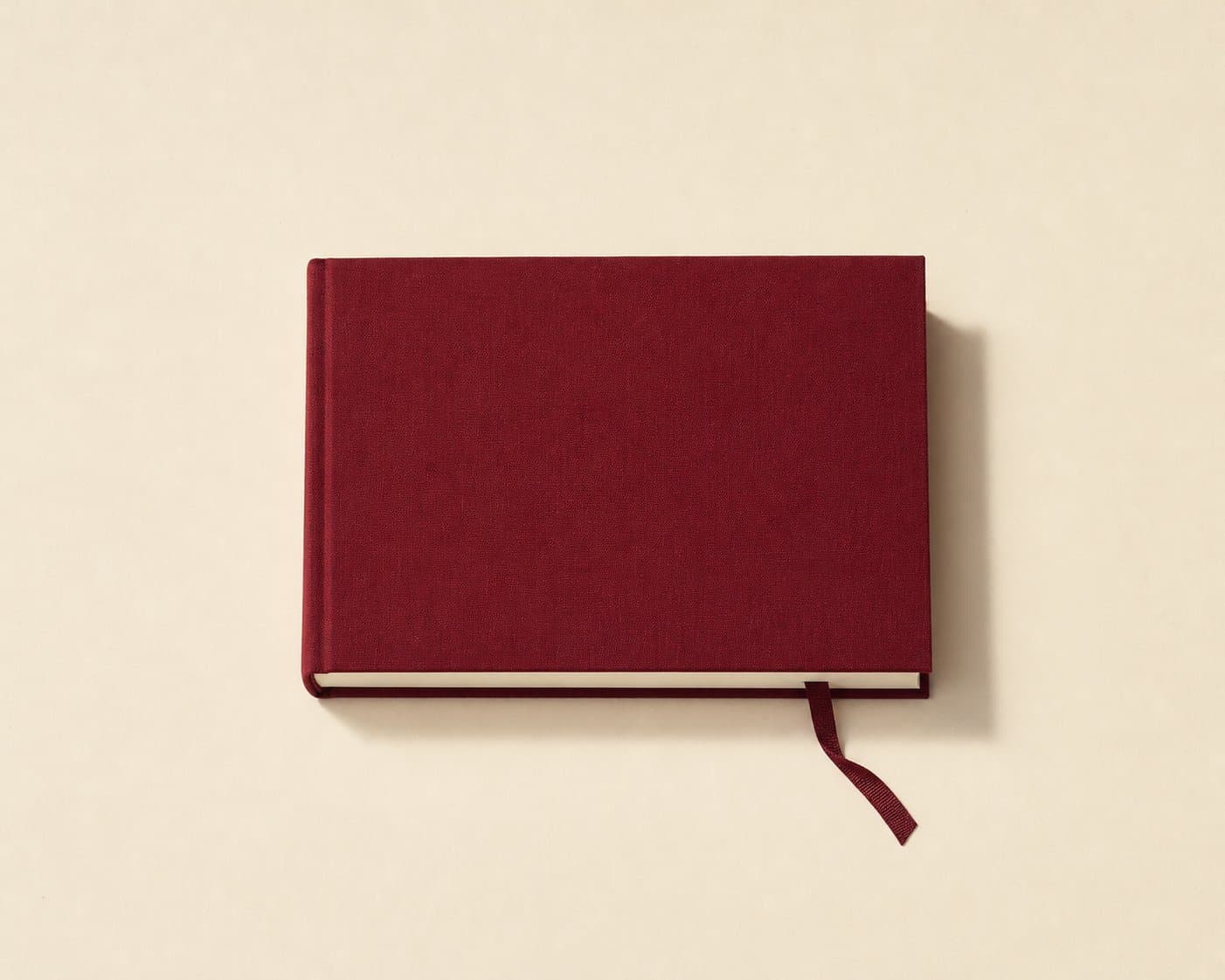A bound maroon notebook with ribbon, centred on cream paper