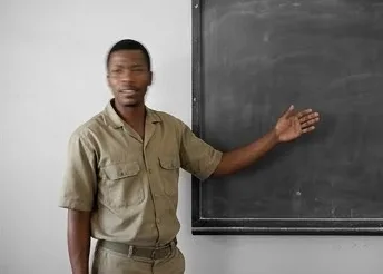 A teacher mid-gesture at the blackboard, from the master set