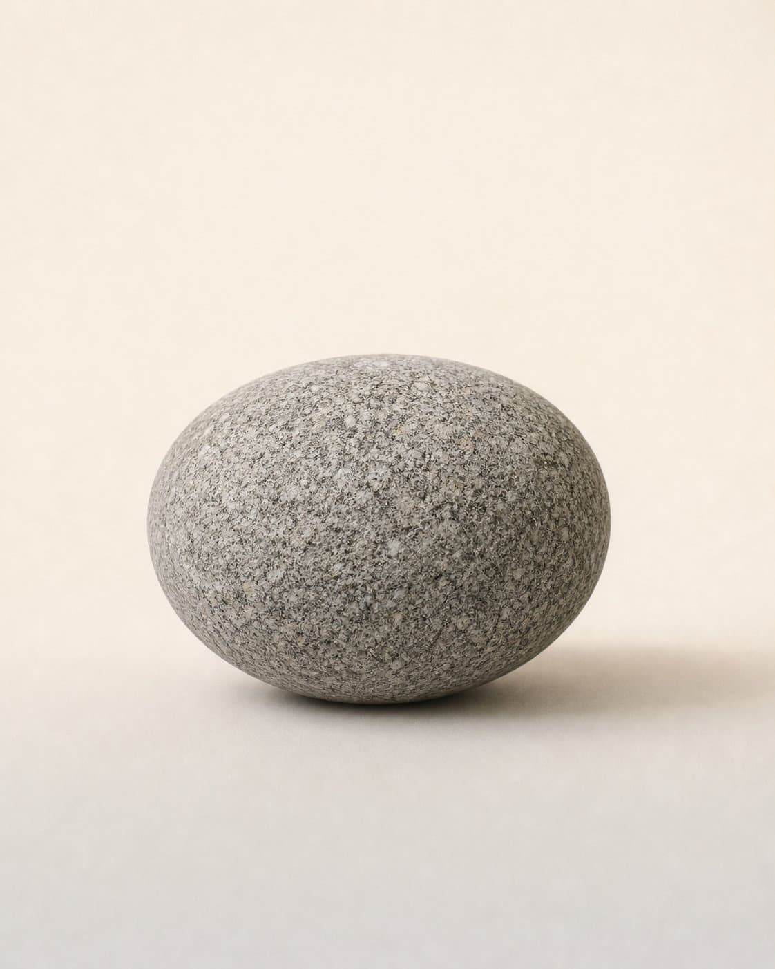 One weathered stone specimen, centred on cream paper