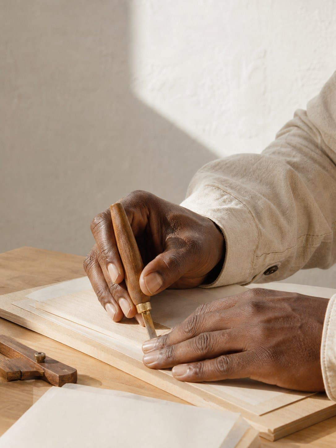 A pair of hands mid-task in a shaft of hard daylight